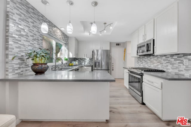 kitchen with sink, appliances with stainless steel finishes, white cabinets, decorative light fixtures, and kitchen peninsula