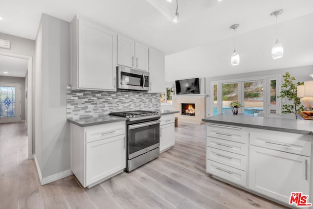 kitchen featuring white cabinetry, stainless steel appliances, decorative light fixtures, and backsplash