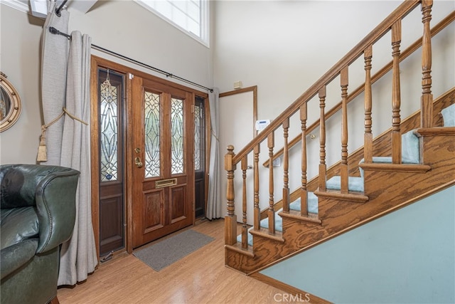 entrance foyer with a towering ceiling and light hardwood / wood-style flooring