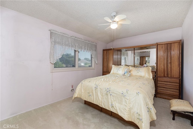 bedroom with a textured ceiling, vaulted ceiling, light colored carpet, and ceiling fan