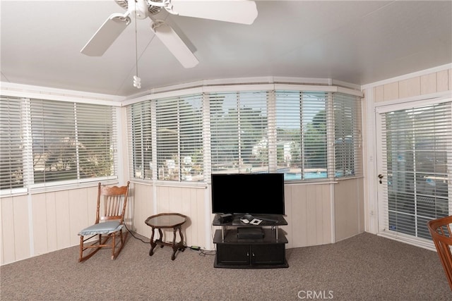 living area with carpet floors, plenty of natural light, and wooden walls