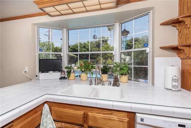 kitchen with dishwasher, sink, tile counters, and ornamental molding