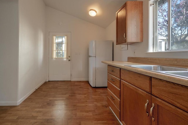 kitchen featuring white refrigerator, light hardwood / wood-style floors, and vaulted ceiling