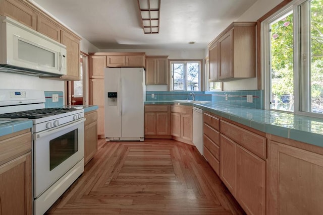 kitchen featuring light brown cabinetry, sink, tile counters, white appliances, and light parquet flooring