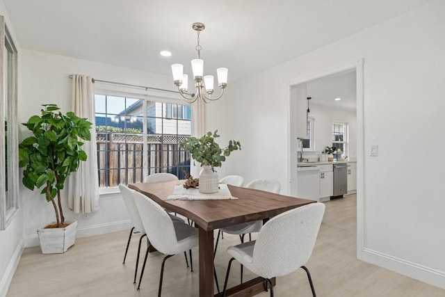 dining space featuring a healthy amount of sunlight, light hardwood / wood-style flooring, and a notable chandelier