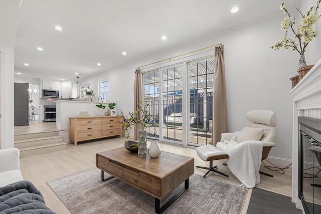 living room with ornamental molding and light wood-type flooring