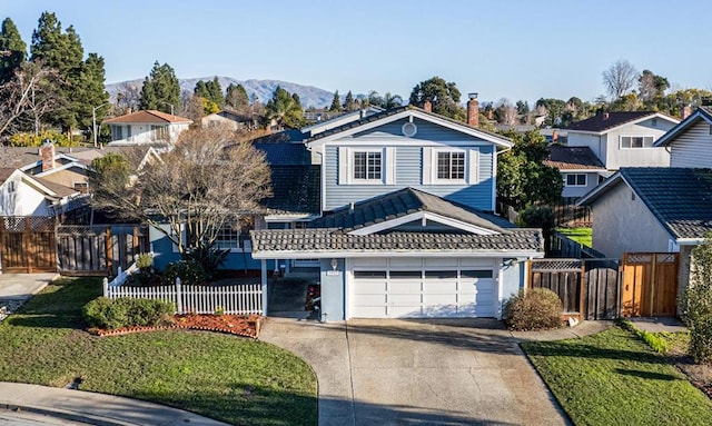 front facade with a mountain view, a garage, and a front yard