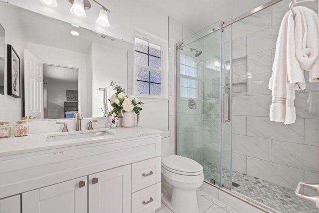 bathroom featuring vanity, toilet, and a shower with shower door