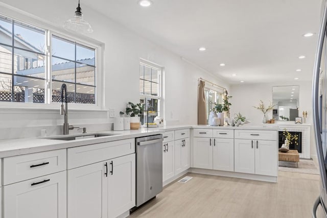 kitchen featuring pendant lighting, sink, light hardwood / wood-style floors, white cabinets, and stainless steel dishwasher