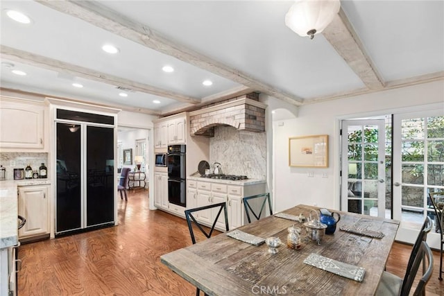 dining space with beamed ceiling, dark hardwood / wood-style floors, and french doors