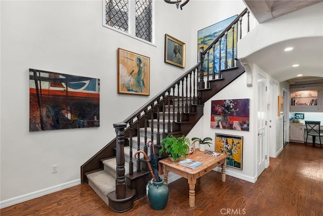 staircase featuring wood-type flooring and a high ceiling