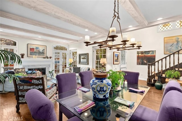 dining space featuring hardwood / wood-style flooring, a fireplace, french doors, and beamed ceiling