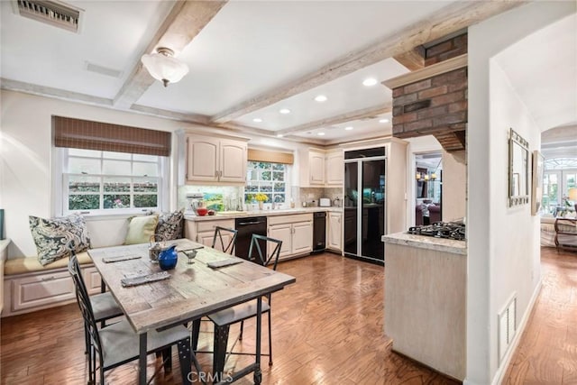 kitchen with beam ceiling, dark hardwood / wood-style floors, black dishwasher, a healthy amount of sunlight, and stainless steel gas stovetop