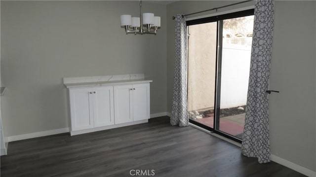 unfurnished dining area with an inviting chandelier and dark hardwood / wood-style flooring