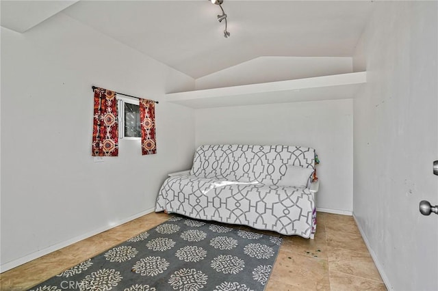 bedroom featuring vaulted ceiling, rail lighting, and baseboards