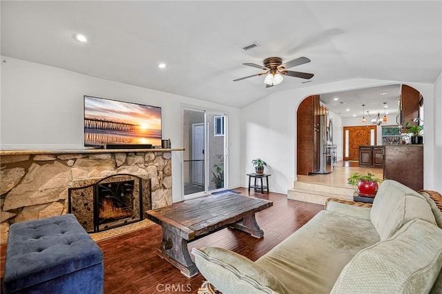living room with arched walkways, ceiling fan with notable chandelier, wood finished floors, and lofted ceiling