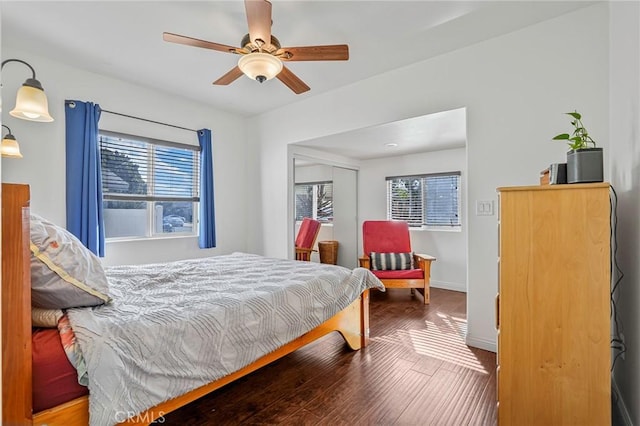 bedroom featuring ceiling fan, baseboards, wood finished floors, and multiple windows