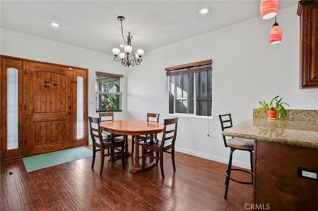 dining area with dark wood-type flooring, an inviting chandelier, baseboards, and recessed lighting