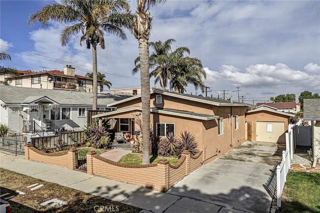 view of front of property featuring a gate, a fenced front yard, concrete driveway, and stucco siding