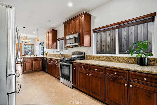 kitchen featuring light stone counters, a chandelier, light tile patterned flooring, stainless steel appliances, and a sink