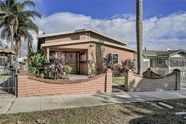 view of front facade featuring a gate, a fenced front yard, and stucco siding