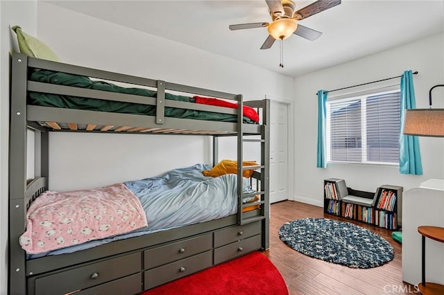 bedroom with ceiling fan, baseboards, and wood finished floors