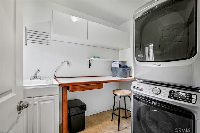 laundry area with stacked washer and dryer, cabinet space, baseboards, and a sink