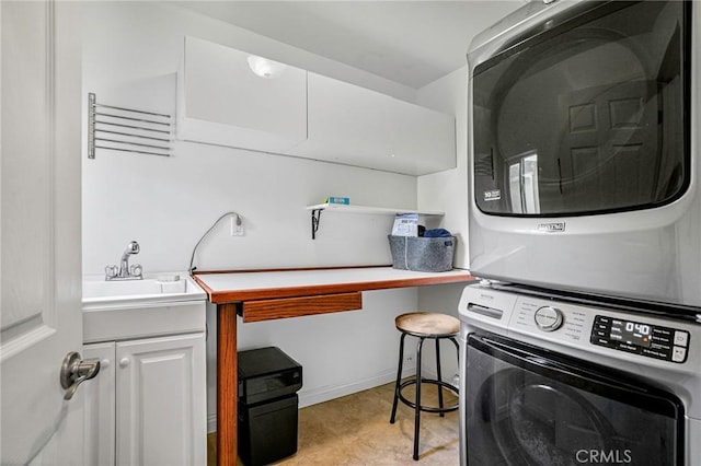 clothes washing area with cabinet space, stacked washer and dryer, and a sink