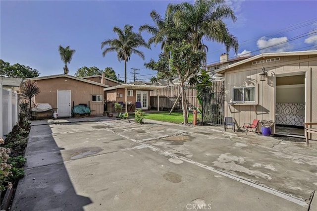 back of property with an outbuilding, a patio area, and fence