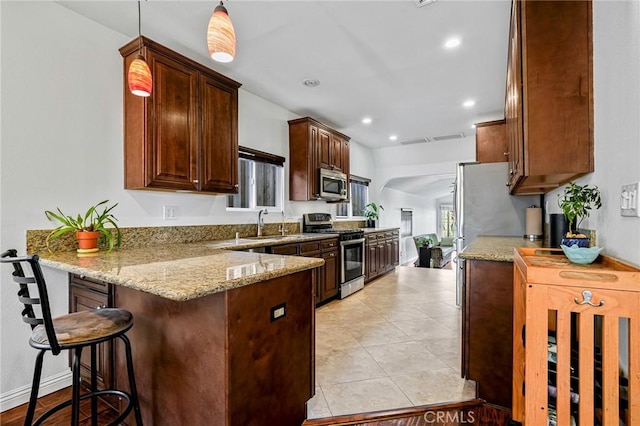 kitchen with a breakfast bar, recessed lighting, stainless steel appliances, a peninsula, and light stone countertops