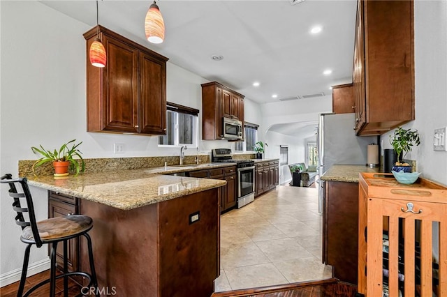 kitchen with stainless steel appliances, decorative light fixtures, light stone countertops, a peninsula, and a kitchen bar