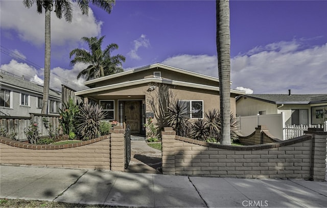 view of front of property with a gate, a fenced front yard, and stucco siding