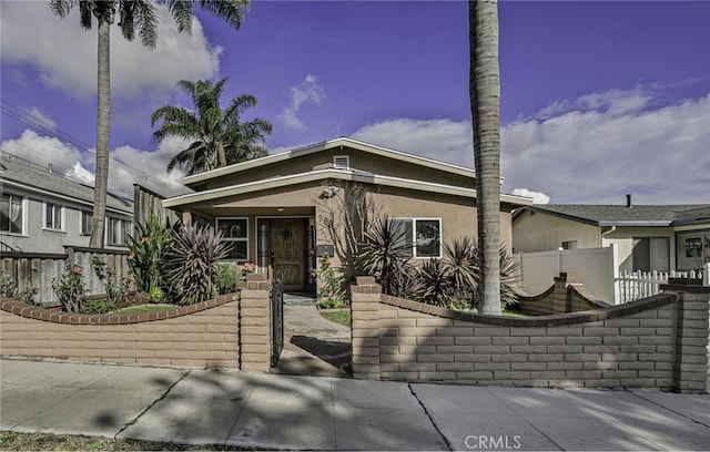 view of front of house featuring stucco siding, a gate, and a fenced front yard