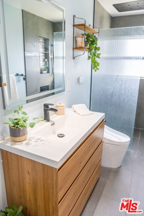 bathroom featuring tile patterned flooring, vanity, walk in shower, and toilet