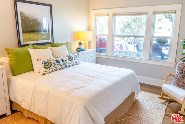 bedroom with multiple windows and light hardwood / wood-style flooring