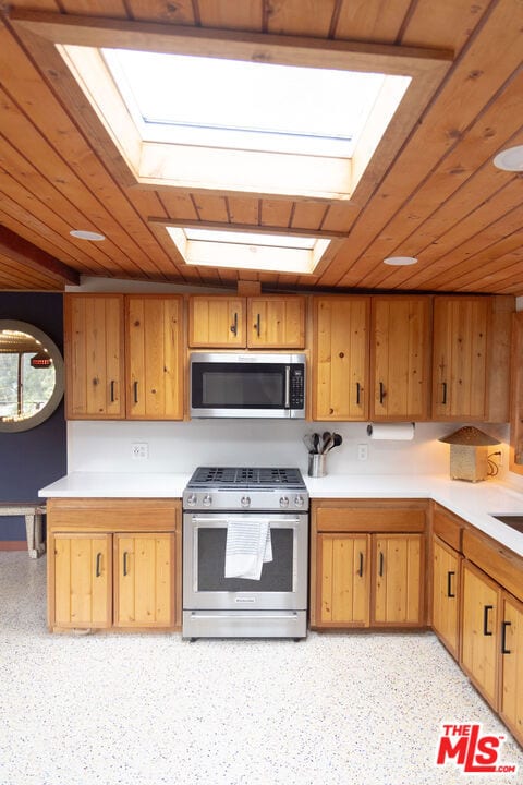 kitchen featuring stainless steel appliances, wood ceiling, and a skylight