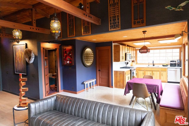 living room featuring a towering ceiling, sink, beam ceiling, and light wood-type flooring