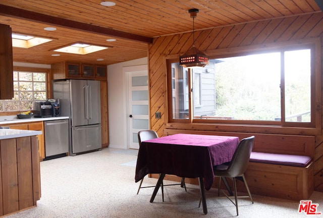 dining room featuring a skylight and wood walls