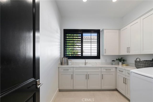 clothes washing area featuring light tile patterned flooring and sink