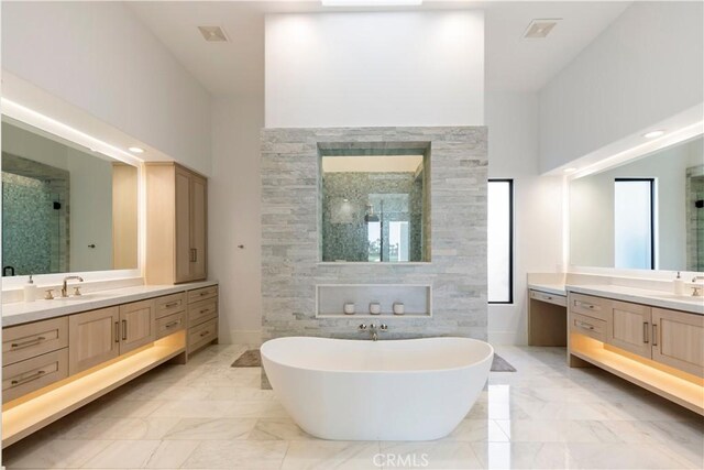 bathroom with a high ceiling, vanity, and independent shower and bath