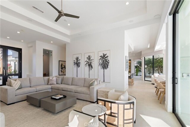 living room with a tray ceiling, french doors, and ceiling fan