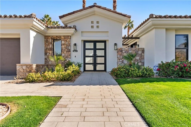 doorway to property with a garage and a lawn