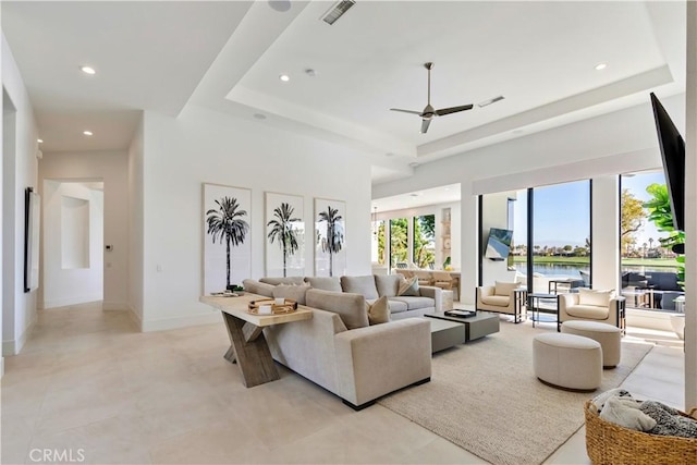 living room with ceiling fan and a tray ceiling