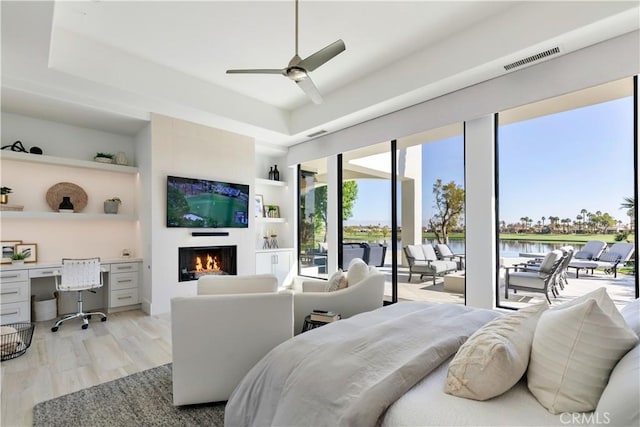 bedroom with ceiling fan, access to exterior, built in desk, and light hardwood / wood-style flooring