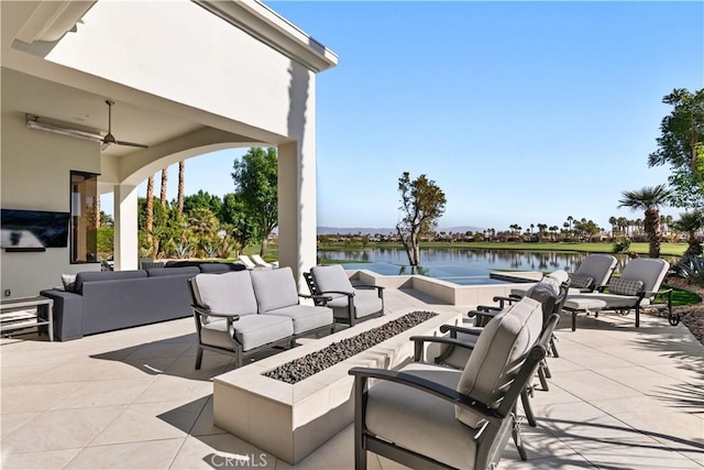 view of patio / terrace featuring a water view, an outdoor living space with a fire pit, and ceiling fan