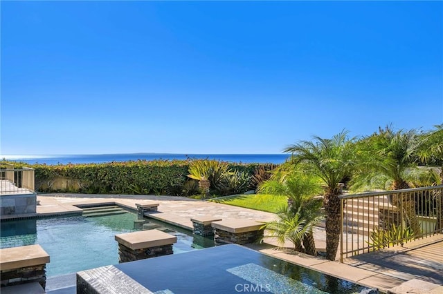 view of pool featuring a jacuzzi, a patio area, and a water view