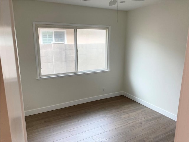 spare room featuring ceiling fan, a wealth of natural light, and light wood-type flooring