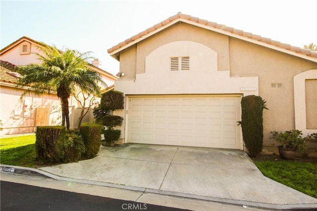 view of front of house featuring a garage, concrete driveway, a tile roof, and stucco siding