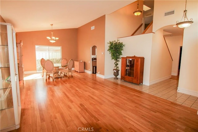 unfurnished dining area with an inviting chandelier, visible vents, arched walkways, and wood finished floors