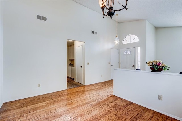 foyer entrance with a high ceiling, hardwood / wood-style floors, and an inviting chandelier